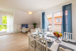 Uma sala de estar moderna com área de jantar, janelas amplas e televisão.