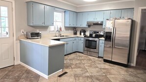 Una cocina con armarios azul claro, un refrigerador de acero inoxidable, un horno empotrado y un tostador.