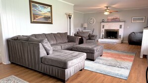 Una sala de estar con sofá modular, reposapiés y chimenea.