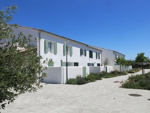 Un edificio blanco con contraventanas verdes y un sendero adoquinado.