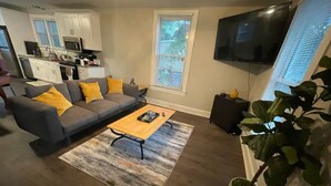 A living room with a gray sofa, yellow cushions, a wooden coffee table, and a large plant. - Private oasis (Charlotte)