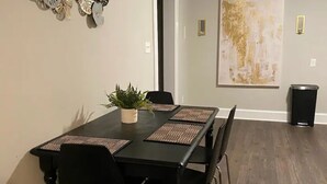 A dining area with a black table and chairs, a potted plant, and a large abstract painting on the wall. - Private oasis (Charlotte)