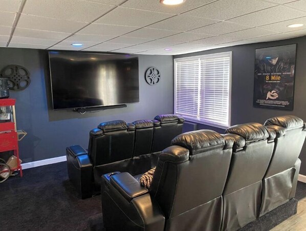 Relax in this cozy home theater room with a large flat-screen TV and comfortable leather recliners.