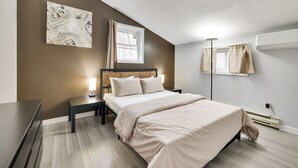 Ein modernes Schlafzimmer mit einem großen Bett, Nachttischen, einem Schreibtisch und einem Fenster mit Vorhängen.