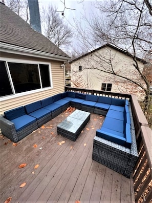 A covered deck with a sectional sofa and a coffee table.