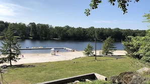 Ein Park am Seeufer mit Sandstrand, einer Holzterrasse und einem Steg, der ins Wasser ragt.