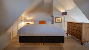 Un dormitorio con una cama grande, un tocador y una lámpara.