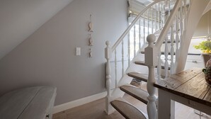 Una escalera con balaustres blancos y barandilla de madera que conduce a una plataforma.
