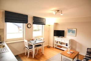 Un espacio habitable compacto con comedor, televisión y una pequeña kitchenette.