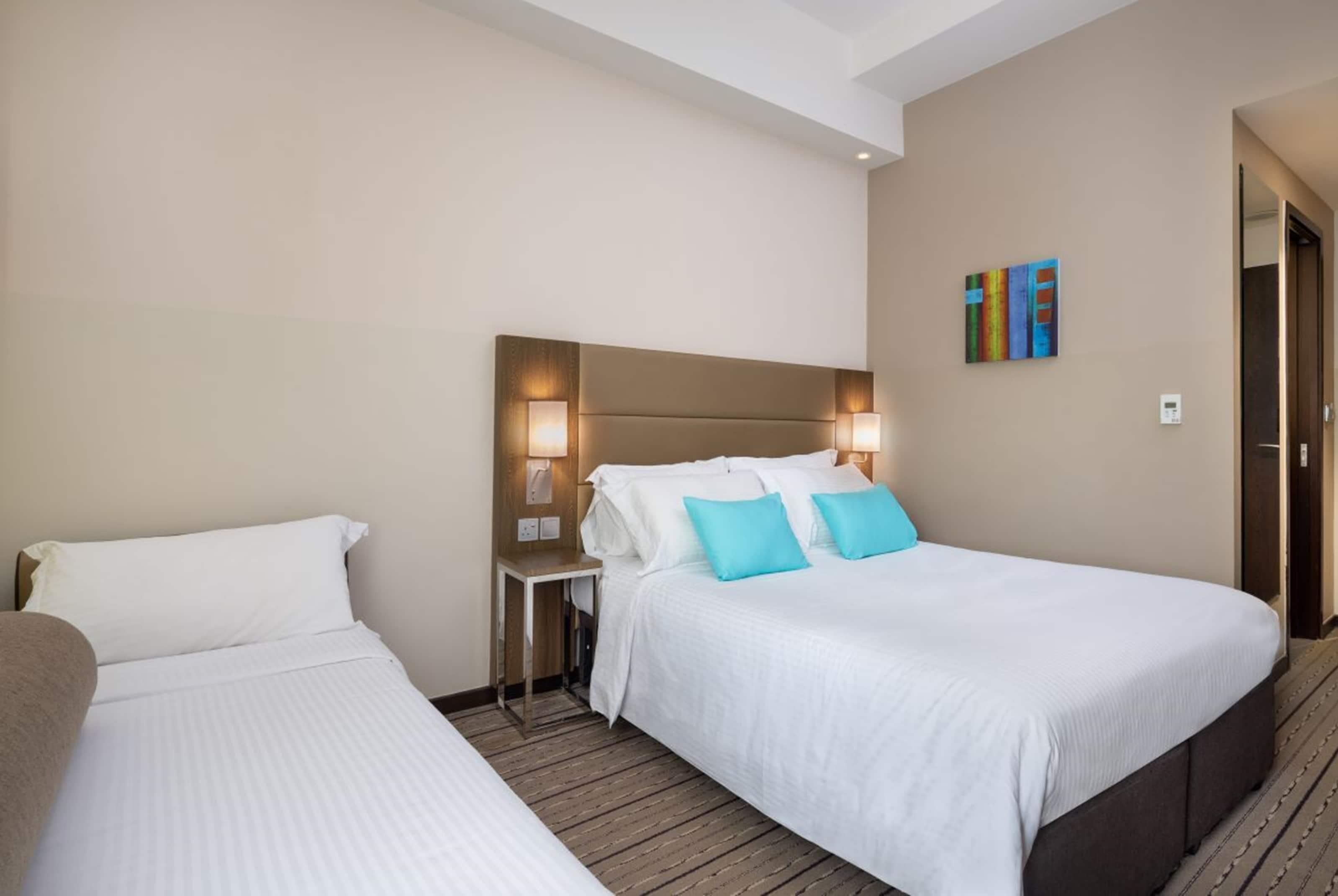 Ein Hotelzimmer mit zwei Betten, einem Nachttisch mit Lampe und einem Gemälde an der Wand.
