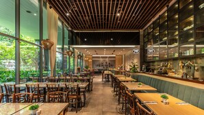 A modern restaurant with a long counter, wooden tables, and chairs. - Hotel Traveltine Downtown Singapore, Trademark Collection by Wyndham (Singapore)