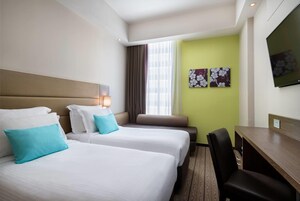 A hotel room with two beds, a desk, and a TV.