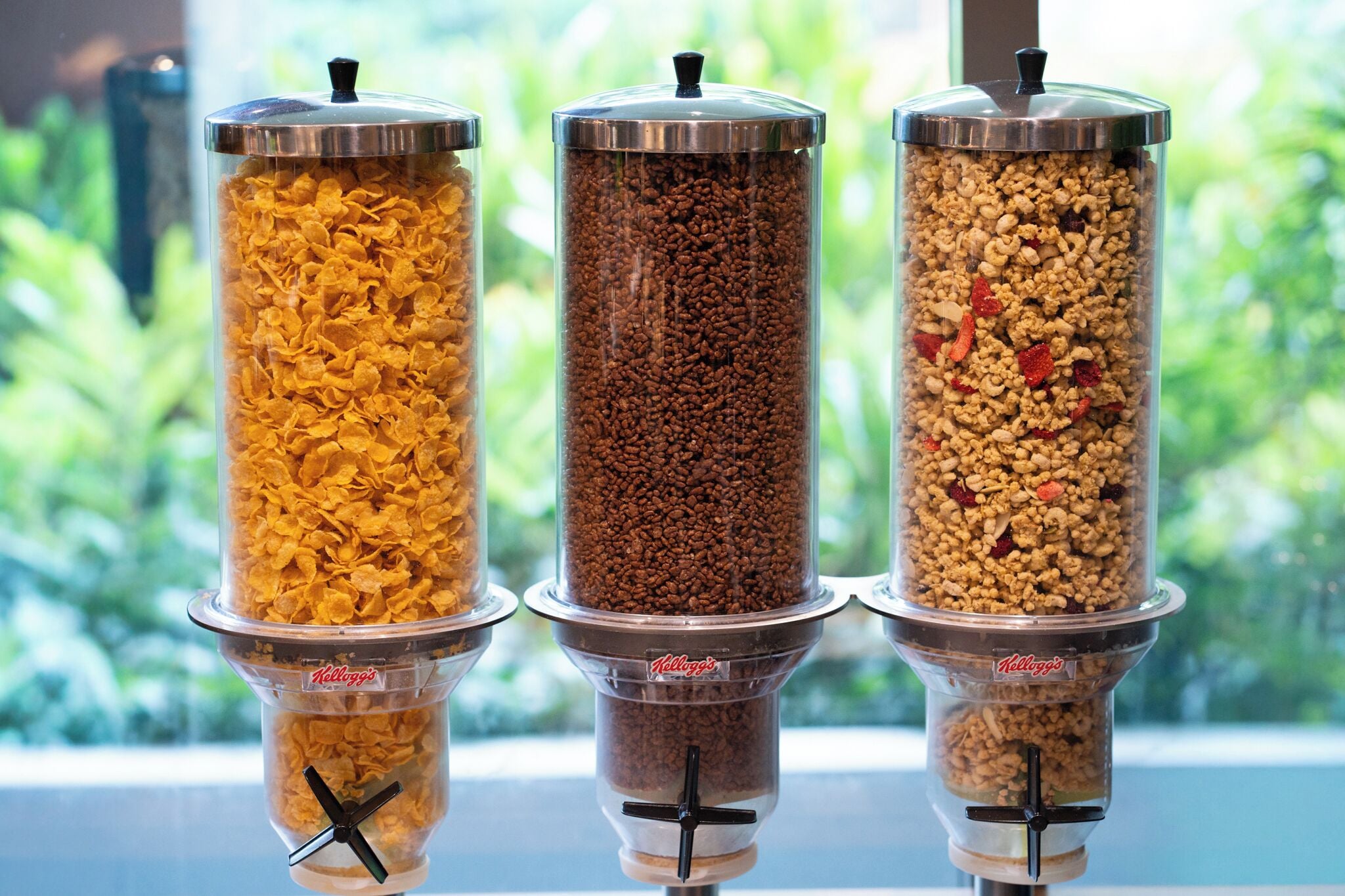 Tres dispensadores cilíndricos con distintos tipos de cereales y frutos secos.