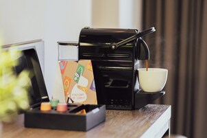 A coffee machine with a cup of coffee on a tray, a box of coffee pods, and a small plant on a wooden table.