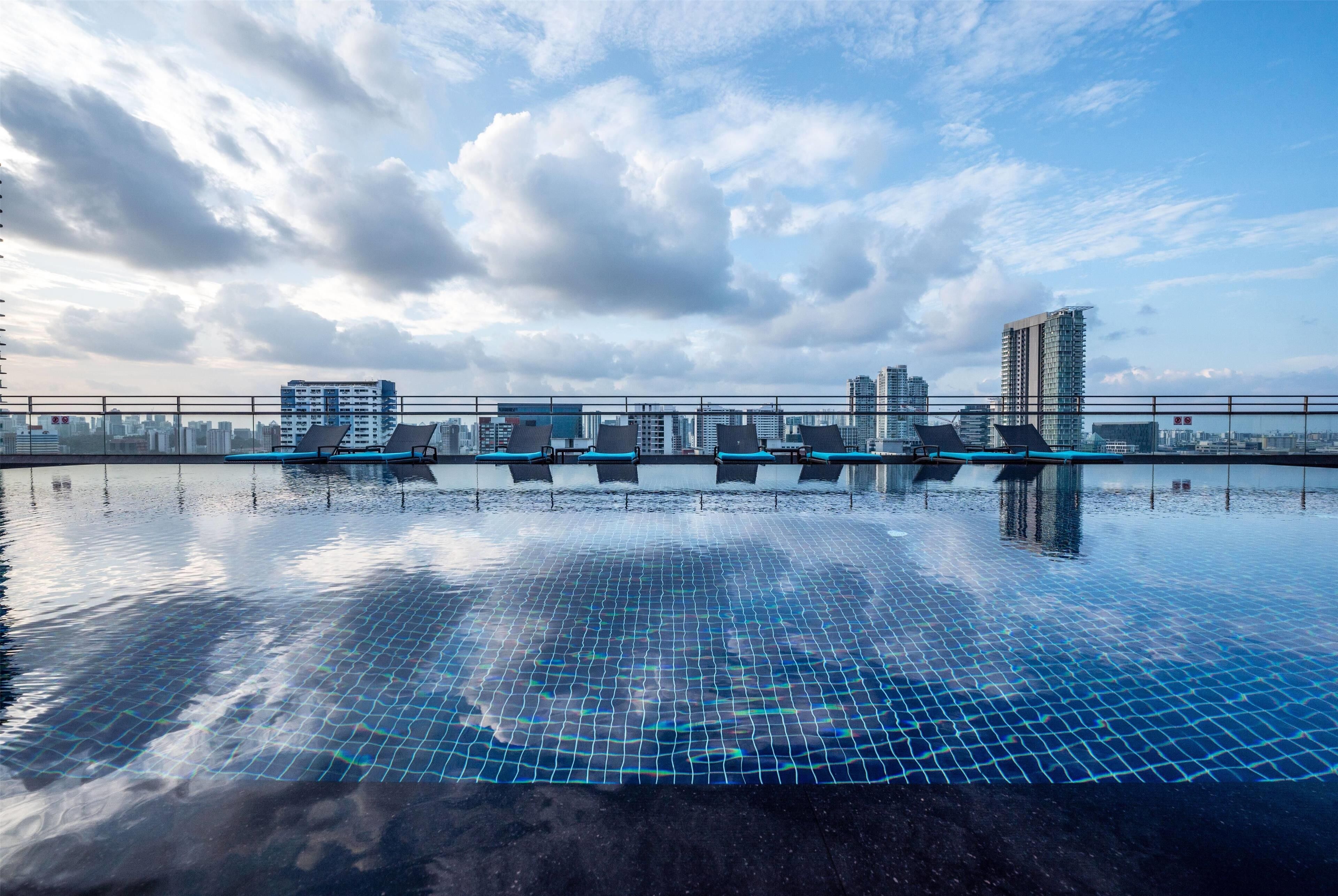 Una piscina en la azotea con vista a un paisaje urbano, incluyendo rascacielos y cielo despejado.