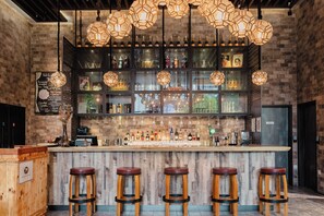 A bar with a wooden counter, multiple stools, and hanging hexagonal light fixtures. - Hotel Traveltine Downtown Singapore, Trademark Collection by Wyndham (Singapore)