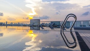 A rooftop pool with a city skyline in the background, a metal pool ladder, and lounge chairs. - Hotel Traveltine Downtown Singapore, Trademark Collection by Wyndham (Singapore)
