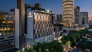A hotel with a modern design, featuring a prominent 'HOTEL TRAVELINE' sign, surrounded by other high-rise buildings and trees. - Hotel Traveltine Downtown Singapore, Trademark Collection by Wyndham (Singapore)