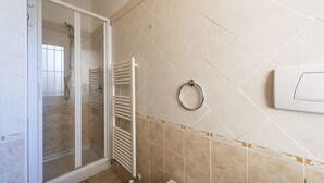 Une salle de bain avec une douche, un porte-serviettes et des toilettes.