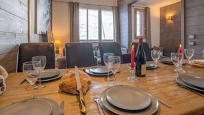 A dining table set for four with a loaf of bread, wine glasses, and a bottle of wine.