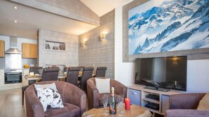 A modern living room with leather sofas, a wooden coffee table, and a large TV.
