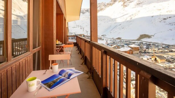 A balcony with wooden railings overlooking a snowy mountain landscape.