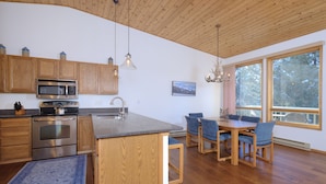 A modern kitchen with wooden cabinets, a built-in microwave, and a large island with seating.