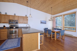 A modern kitchen with wooden cabinets, a built-in microwave, and a large island with seating.