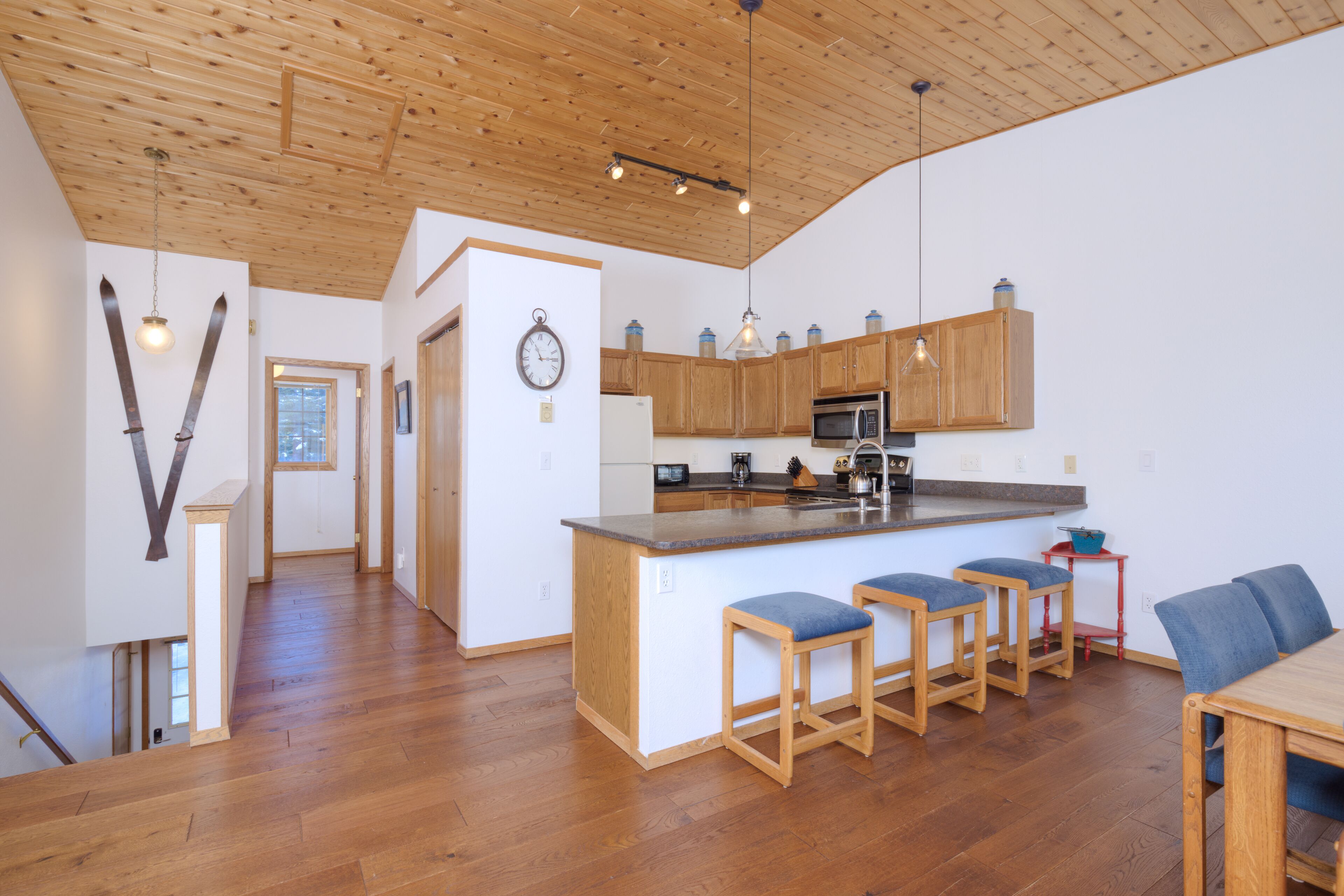 Une cuisine spacieuse avec des meubles en bois, un îlot central doté de tabourets, et un coin repas avec une table et des chaises.
