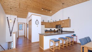 A spacious kitchen with wooden cabinets, a central island with bar stools, and a dining area with a table and chairs.