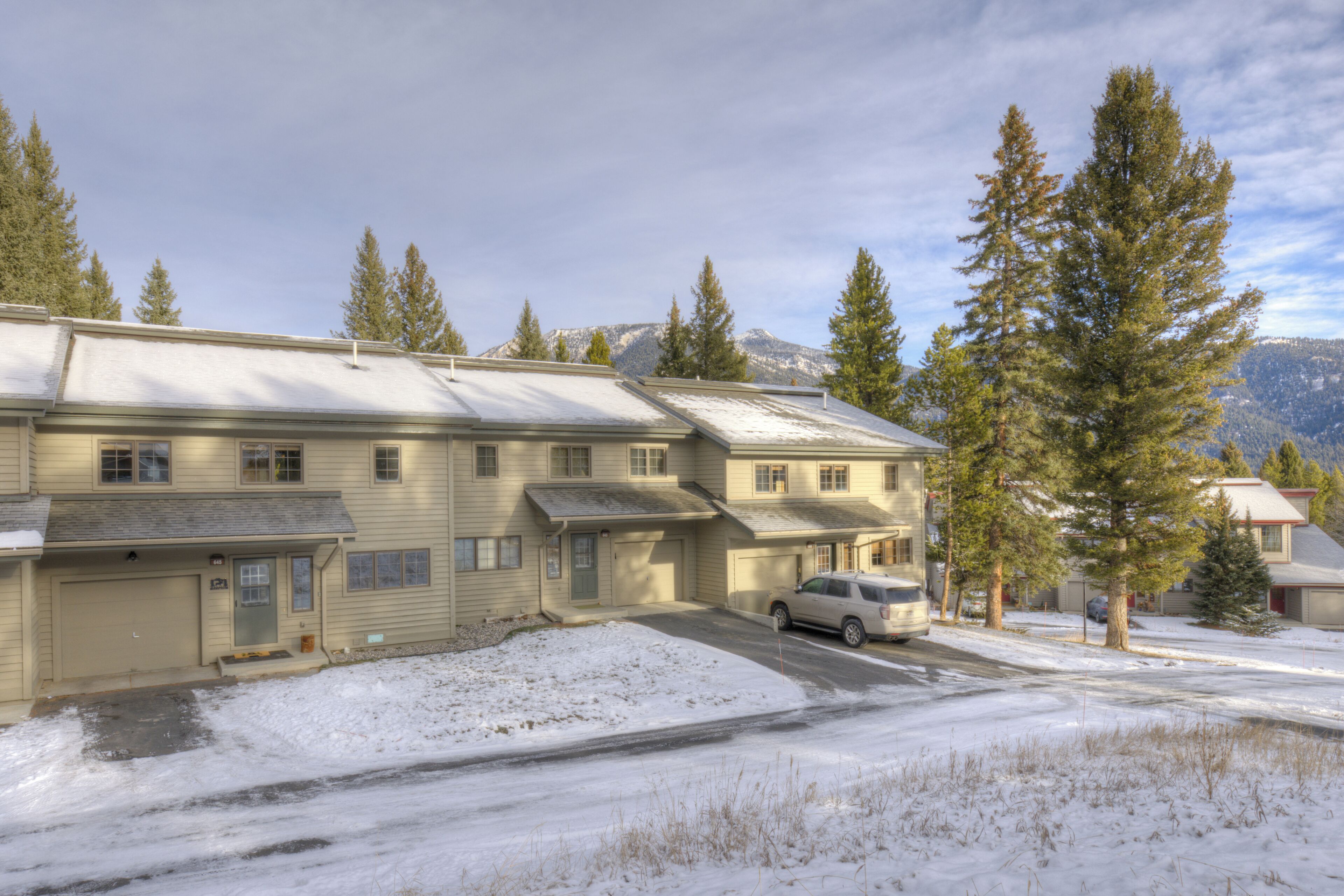 A two-story building with a garage, a driveway, and a car parked in front.