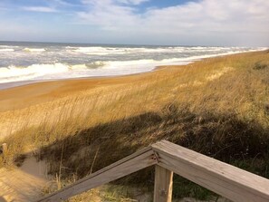 Een strand met een houten looppad dat naar de kust leidt.