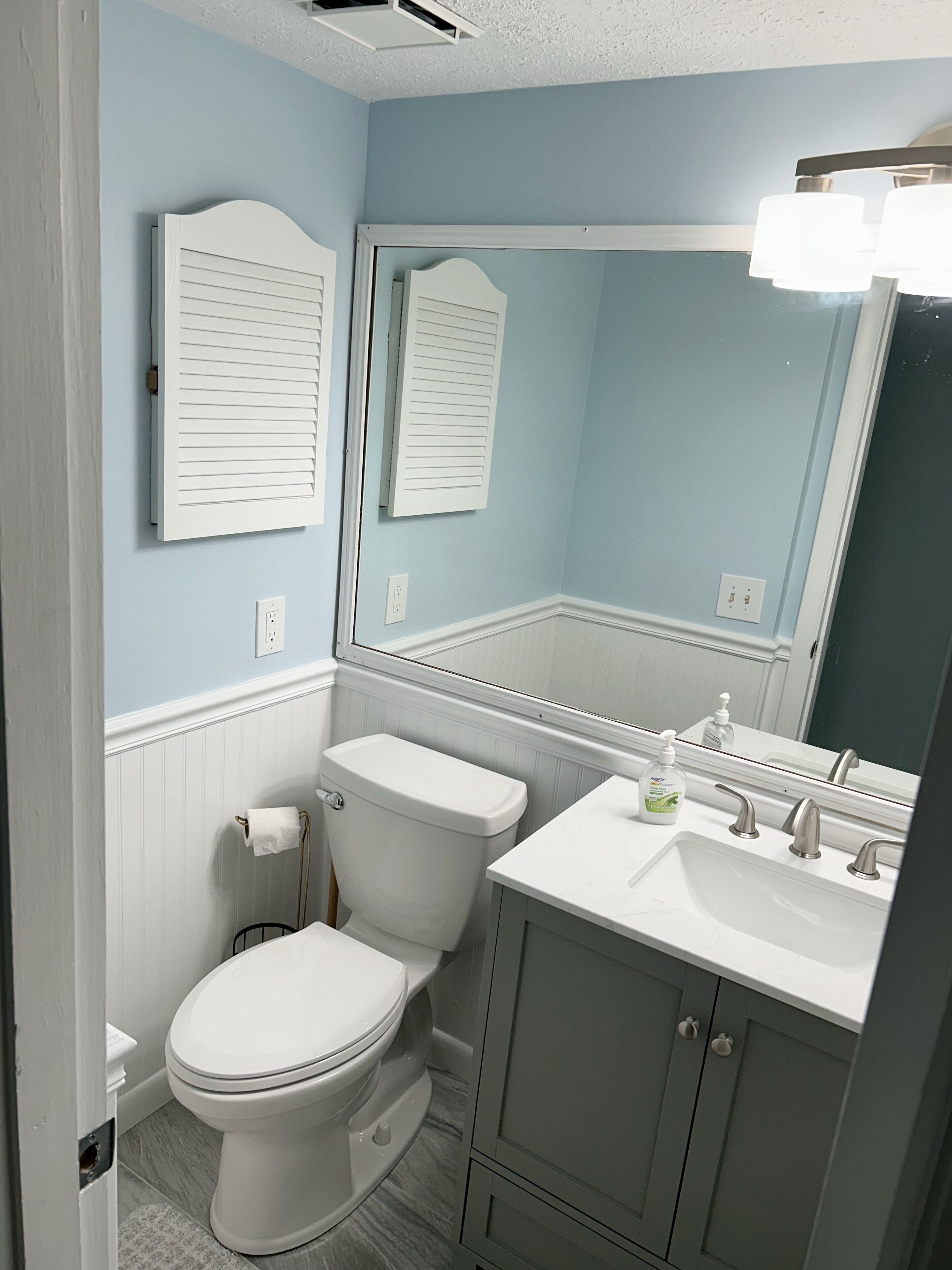 A bathroom with a toilet, sink, and mirror.