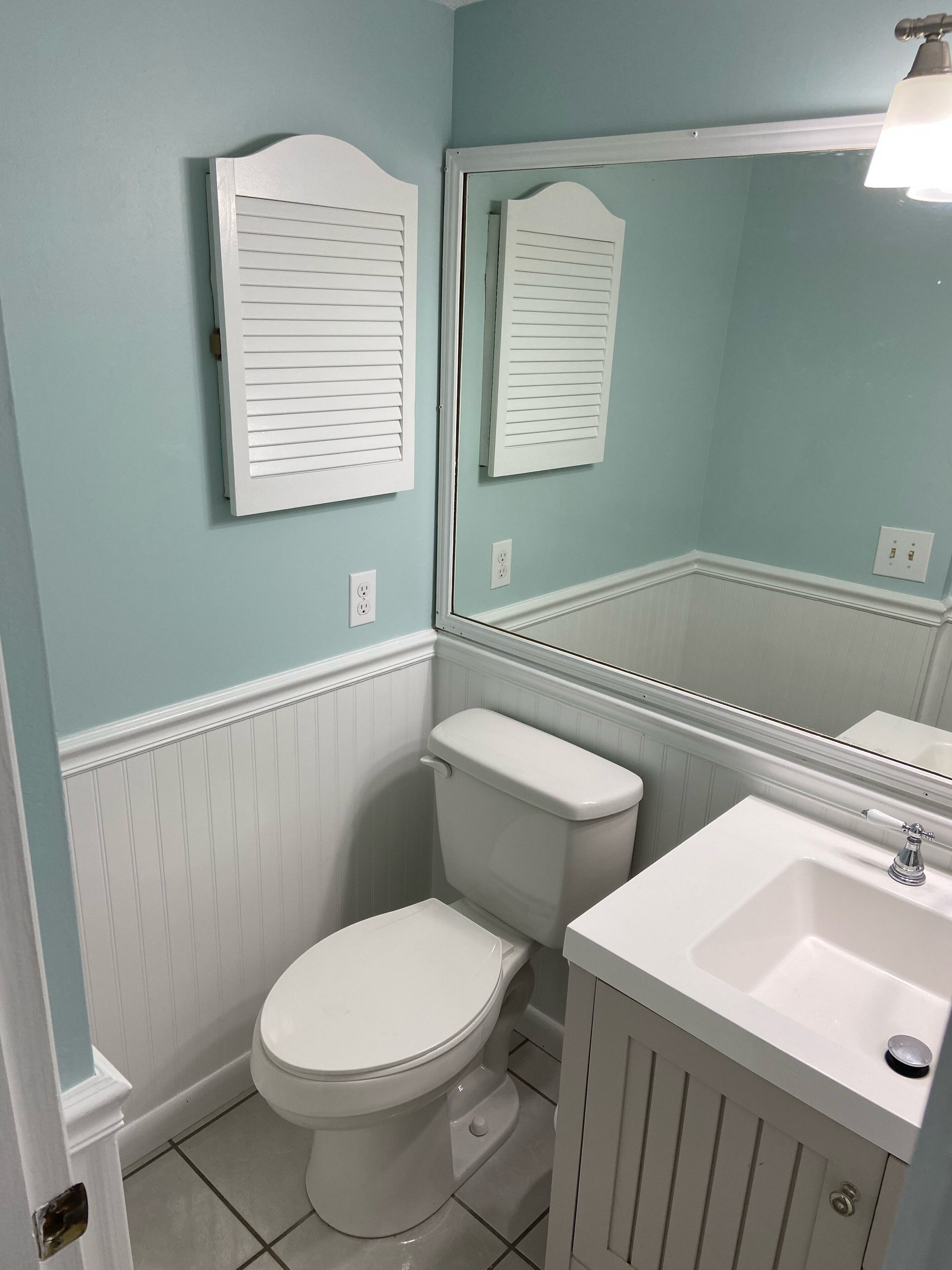 A bathroom with a toilet, sink, and mirror.