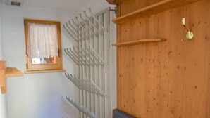 Een kamer met een houten wand, een grijze bank, een raam met gordijn en een witte radiator.