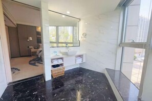 A modern bathroom with a large mirror, white cabinetry, and a black marble floor. - Xiamen Yinhai Blue Hotel (Gaoqi Airport Wuyuan Bay Branch) (Xiamen)