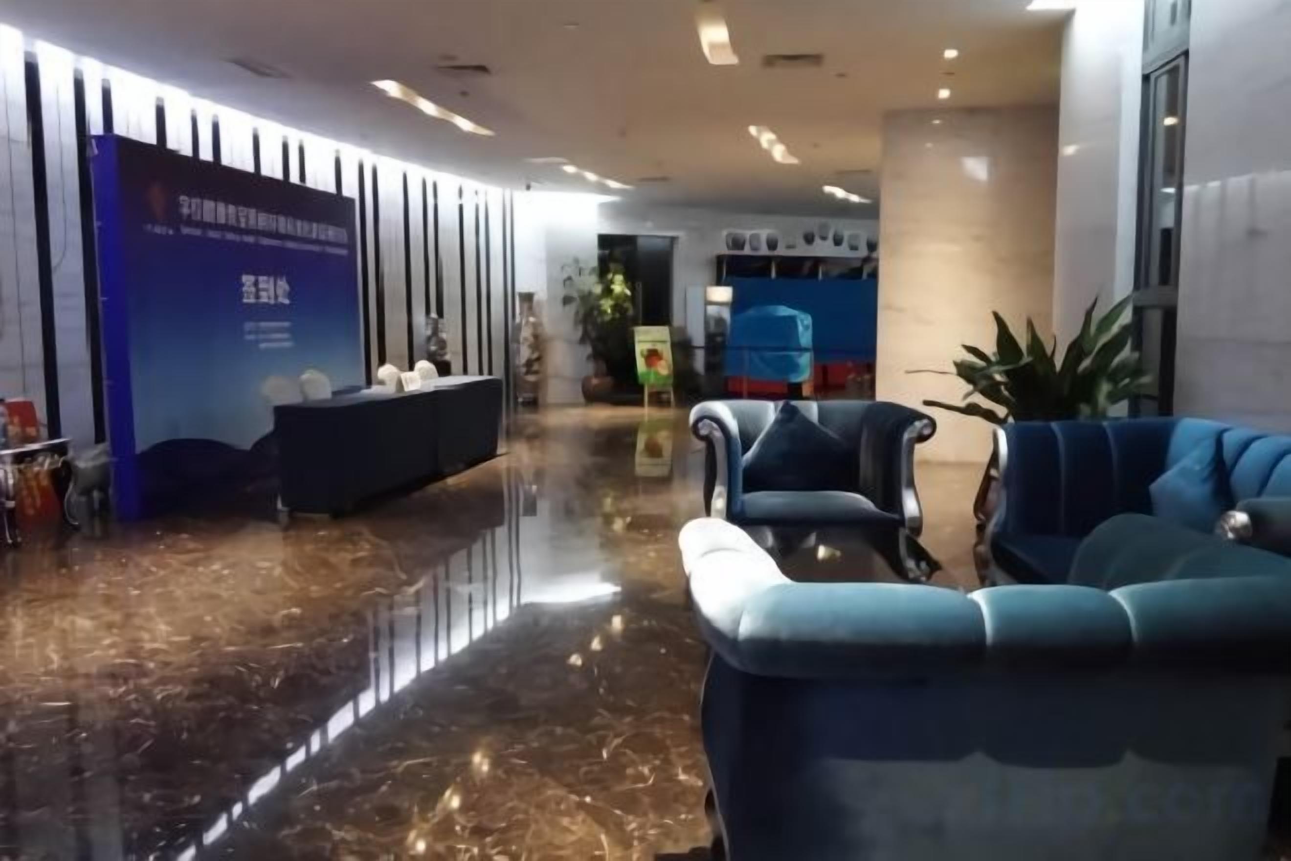 A hotel lobby with a reception desk, seating area, and a plant.