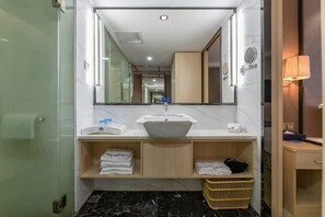 A bathroom with a marble sink, a mirror, a towel rack, and a small basket. - Xiamen Yinhai Blue Hotel (Gaoqi Airport Wuyuan Bay Branch) (Xiamen)