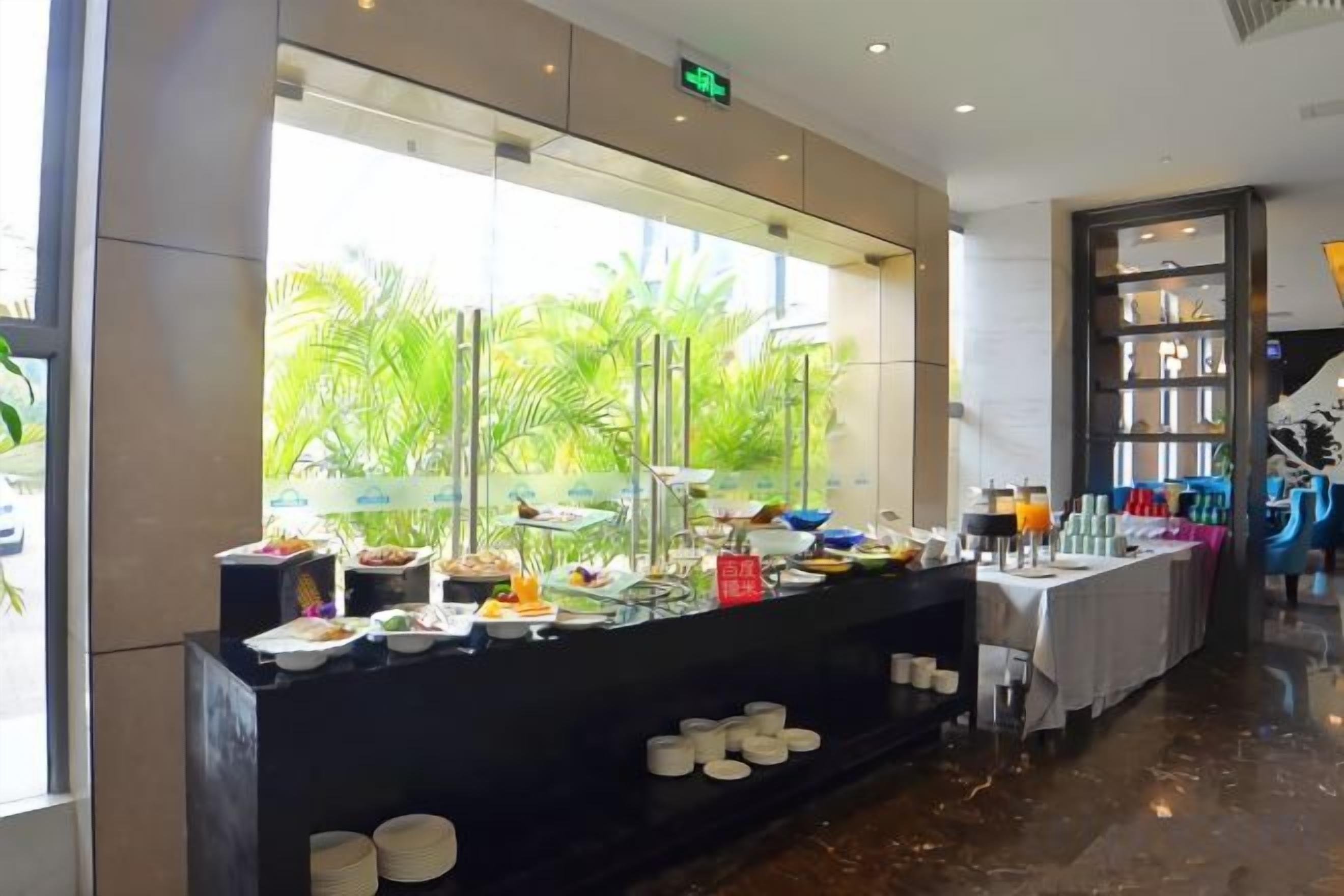 A buffet area with a variety of food items and a view of palm trees through a large window.