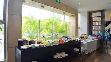 A buffet area with a variety of food items and a view of palm trees through a large window.