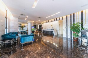 A hotel lobby with a reception desk, seating area, and a polished marble floor. - Xiamen Yinhai Blue Hotel (Gaoqi Airport Wuyuan Bay Branch) (Xiamen)