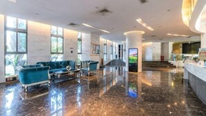 Un hall d’entrée spacieux doté d’un sol en marbre, d’un comptoir de réception et d’un espace détente avec des canapés.