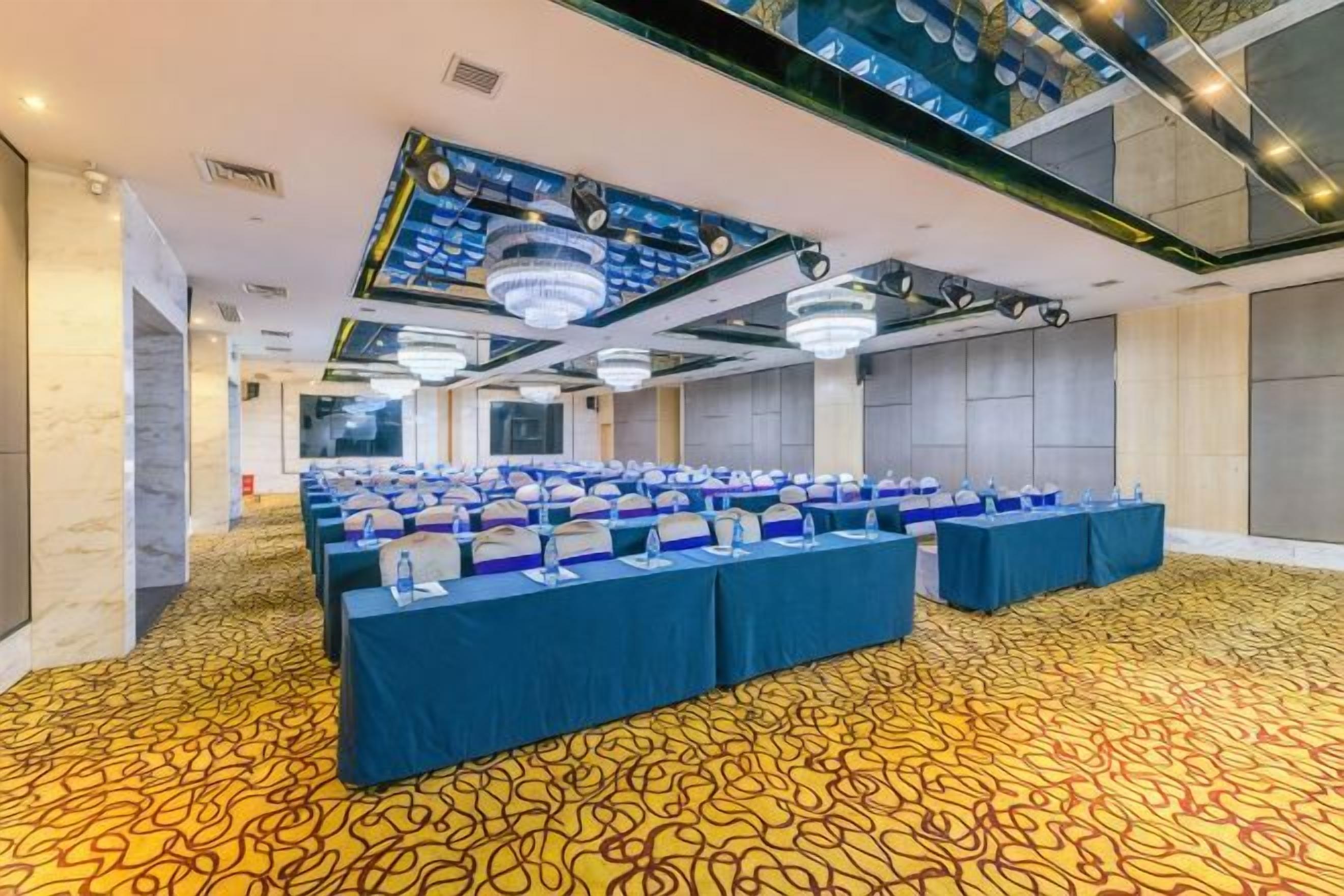 A conference room with rows of tables, a patterned carpet, and a modern ceiling design.