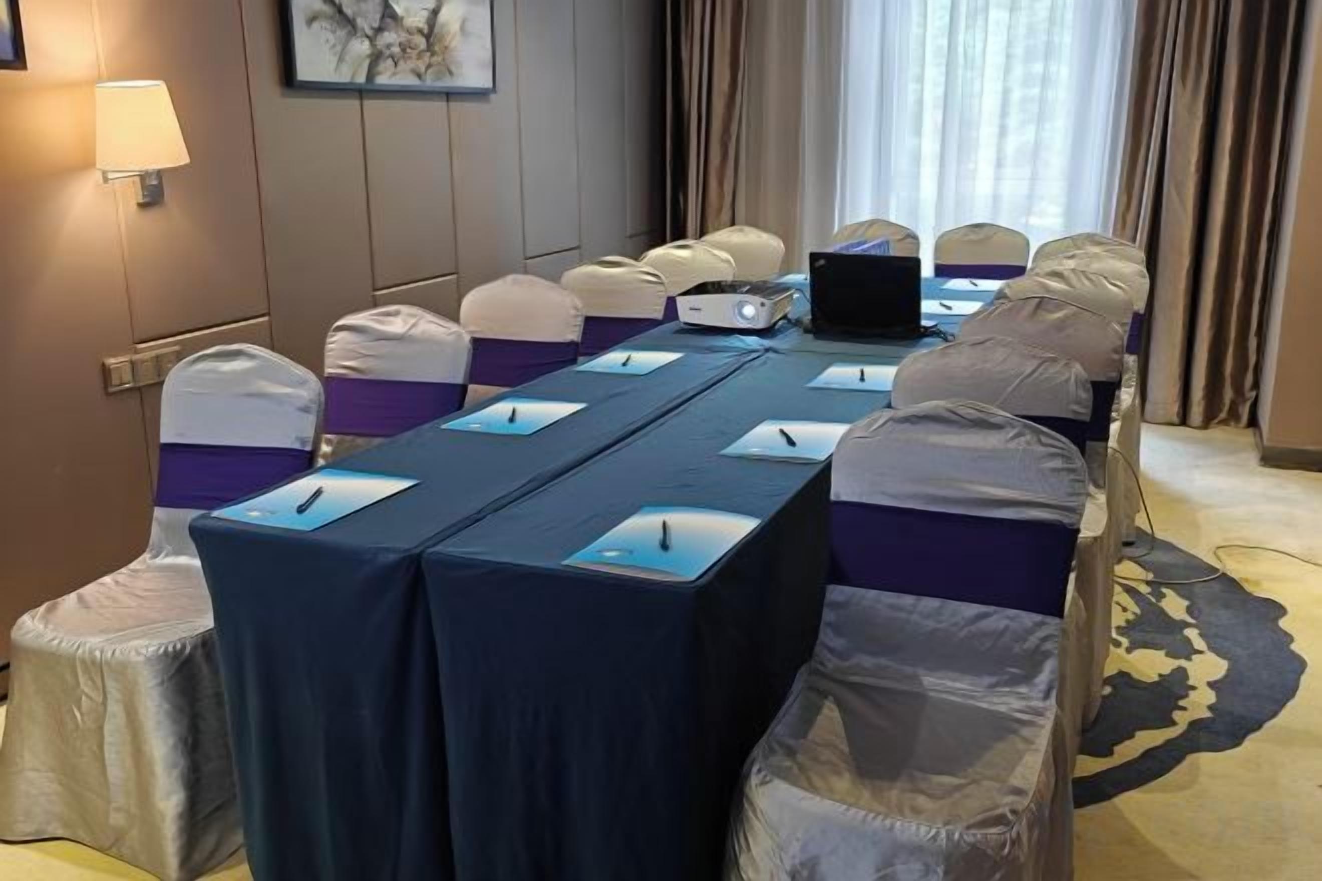 A conference room with a long table, chairs, and a laptop.