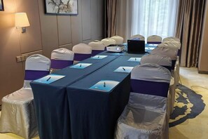 Una sala de conferencias con una larga mesa, sillas y una computadora portátil.