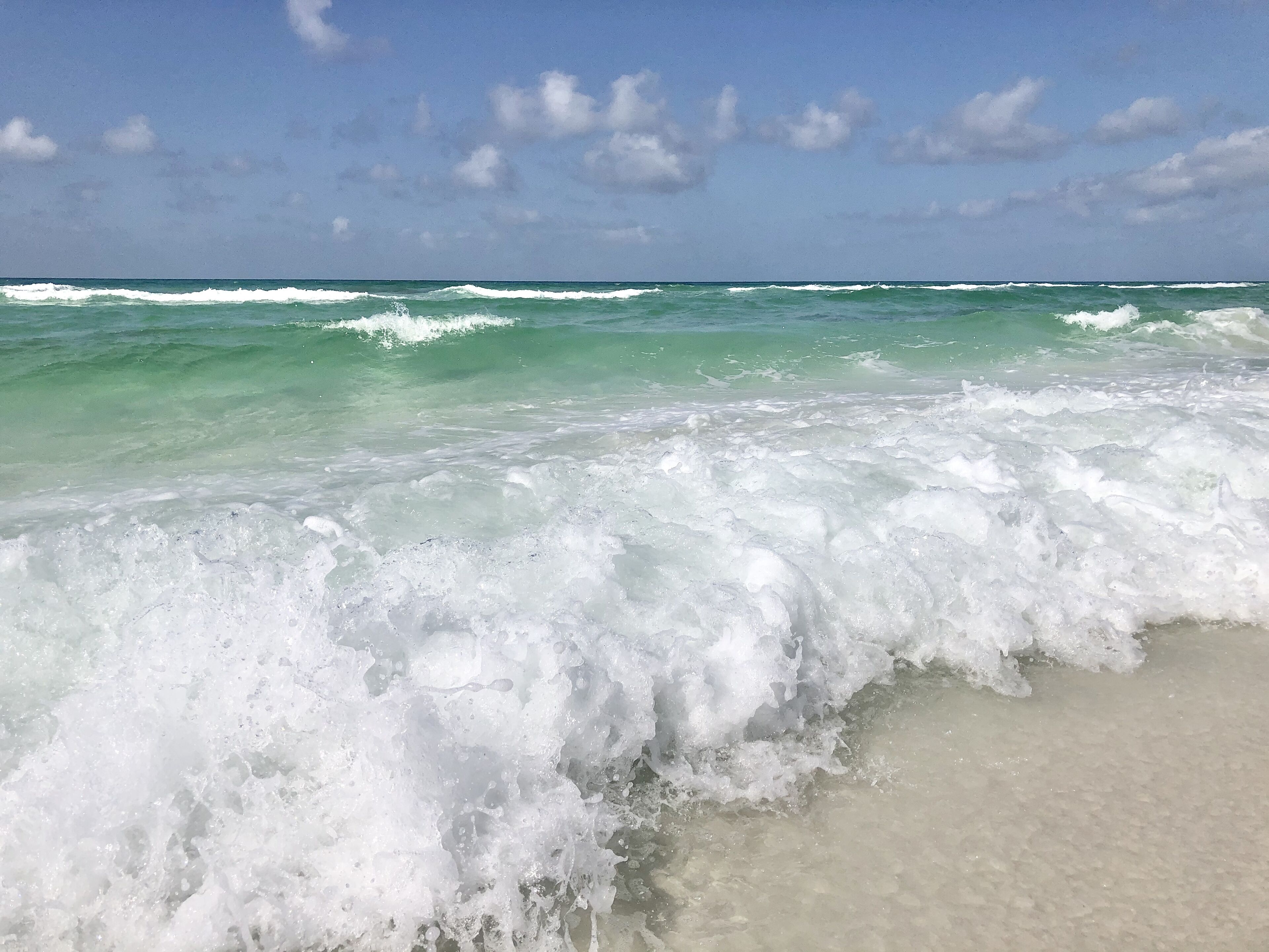 Una playa con olas rompiendo en la orilla bajo un cielo despejado.
