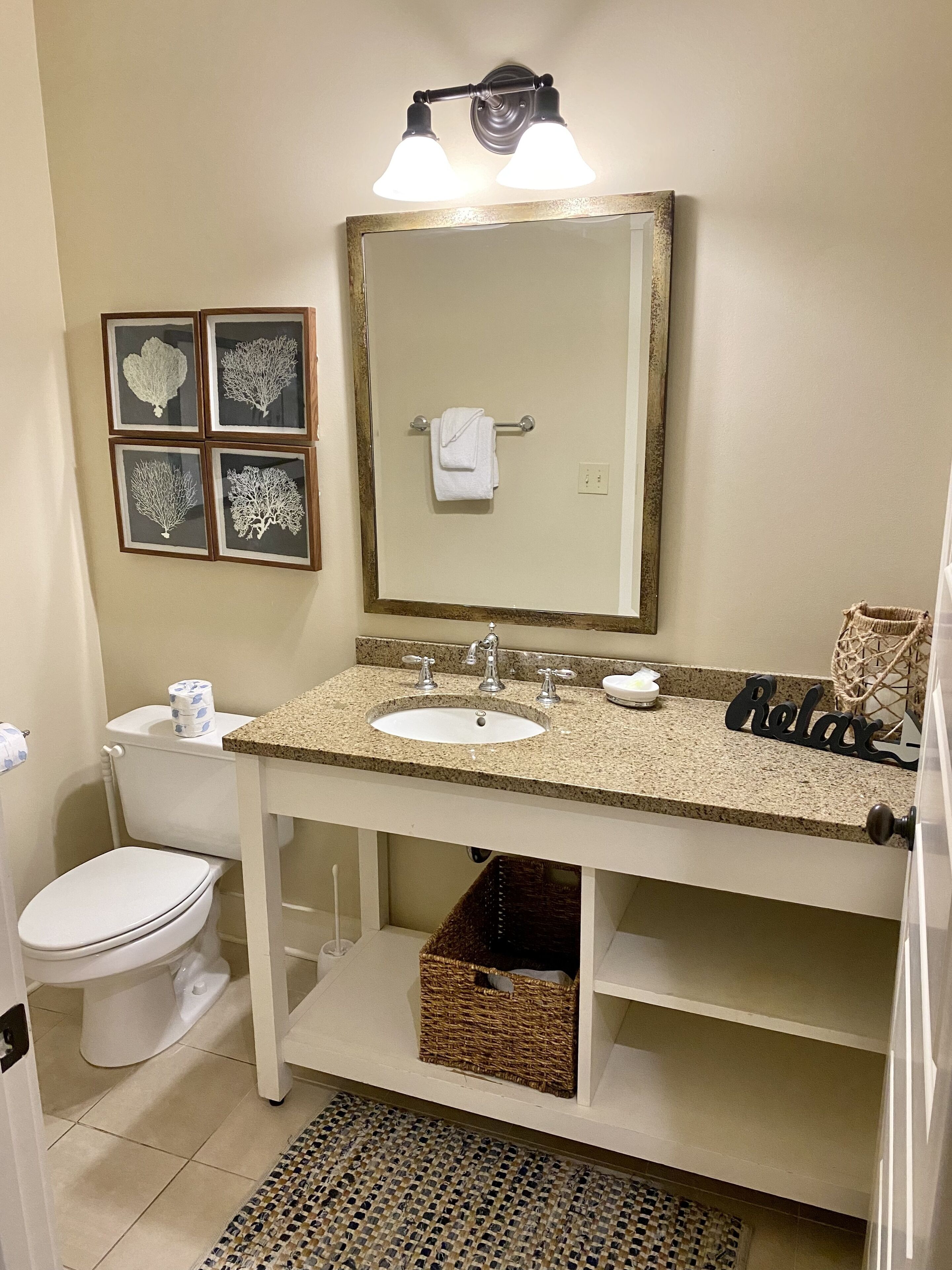 A bathroom with a sink, toilet, framed artwork, and a towel rack.