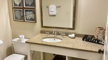 A bathroom with a sink, toilet, framed artwork, and a towel rack.