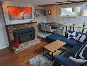 A living room with a fireplace, a dining area, and a sofa with decorative pillows.