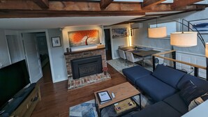 A spacious living room with a fireplace, a dining area, and a sofa. - Be right in the action in our centrally-located 2BR/1BA condo with Hot Tub (Provincetown)
